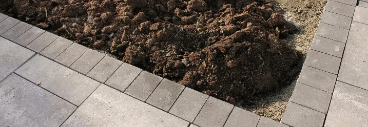 Graue Pflastersteine neben Erde